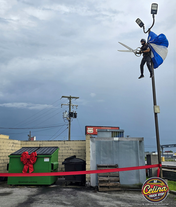 Dumpster Debut Delayed: Scissors-Wielding Parachutist Perched on Pole, Ceremony Halted